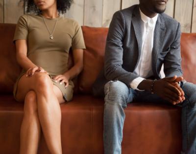 Couple sitting on couch looking unhappy fighting